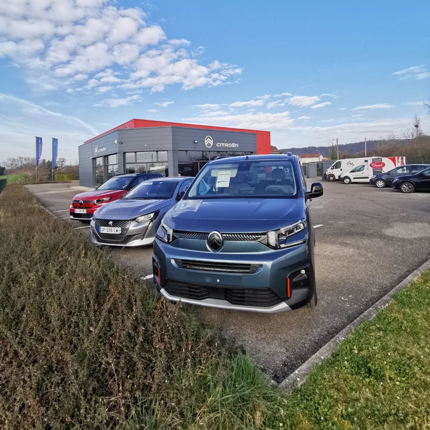 Véhicules stationnés devant un bâtiment automobile sur un parking extérieur