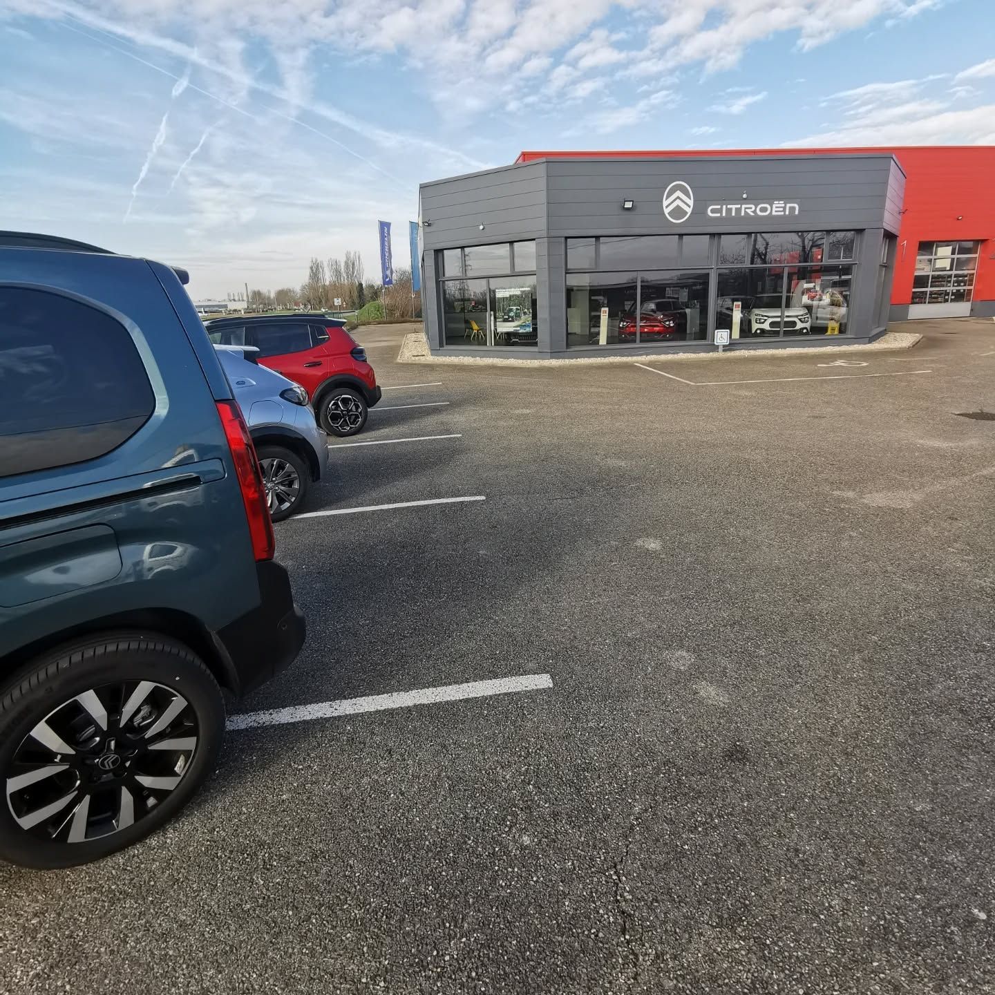 Arrière de voitures stationnées sur un parking en gravier devant un garage