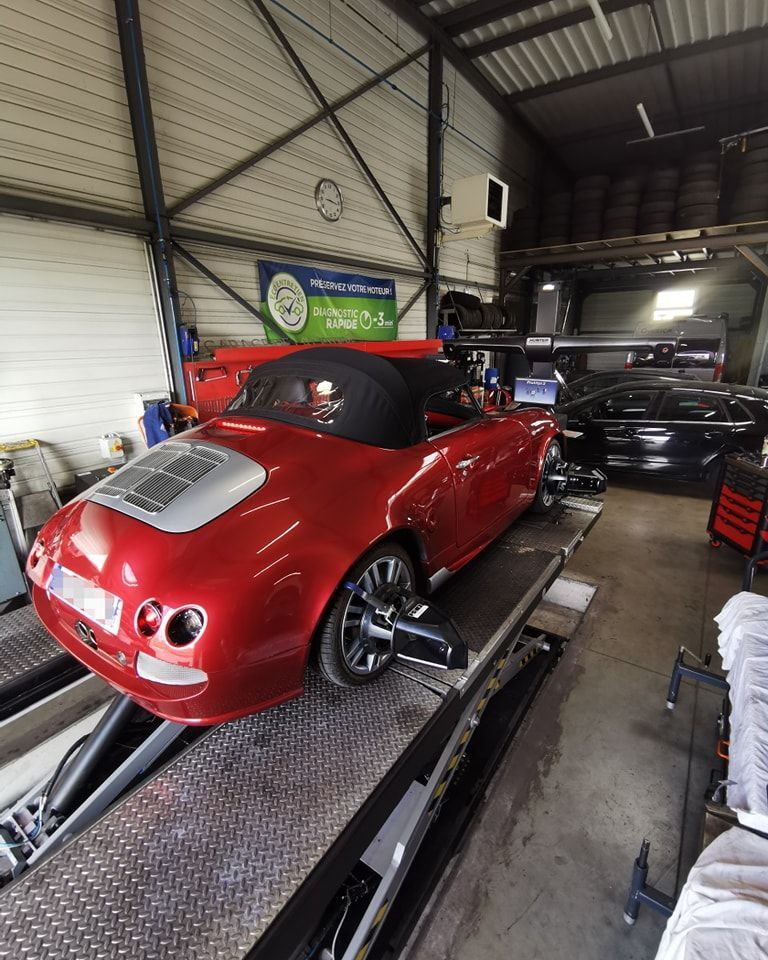 Voiture de sport rouge sur un pont élévateur dans un atelier mécanique