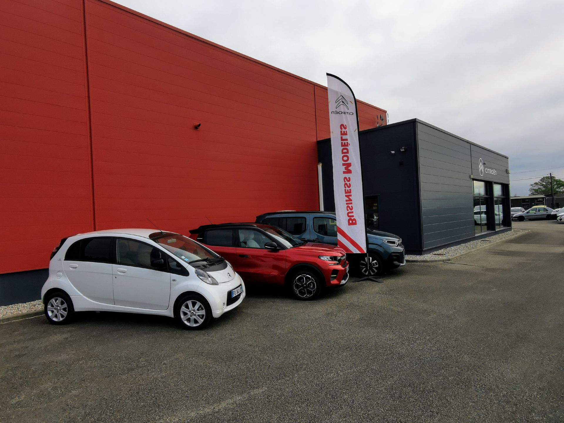 Voitures garées en ligne devant un bâtiment de garage rouge