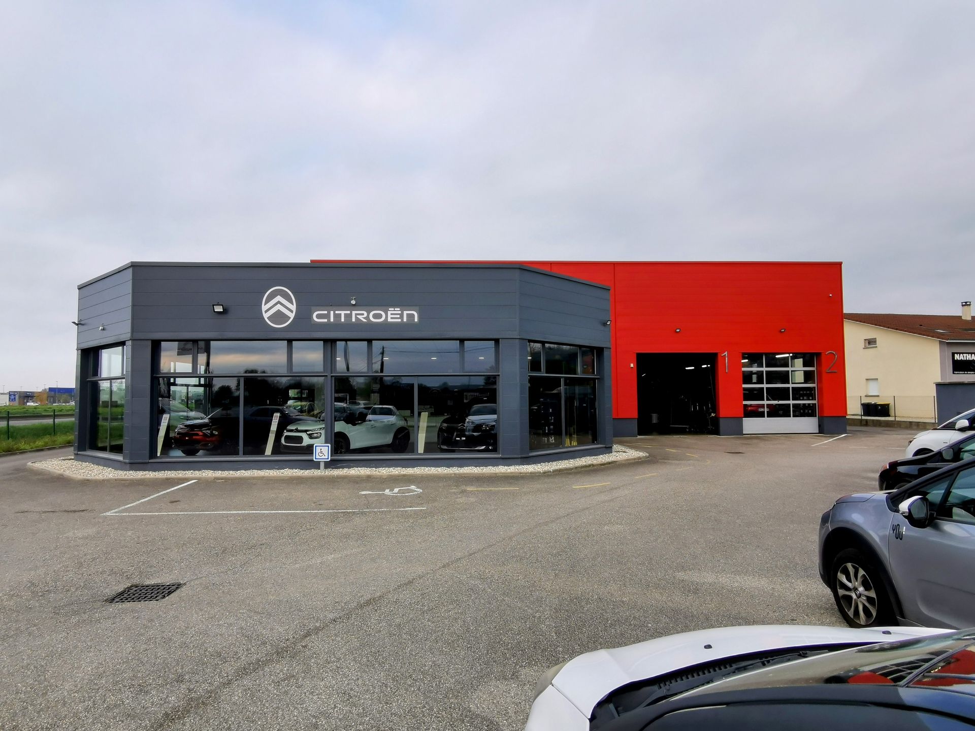 Vue extérieure d'une concession Citroën avec façade vitrée et bâtiment rouge