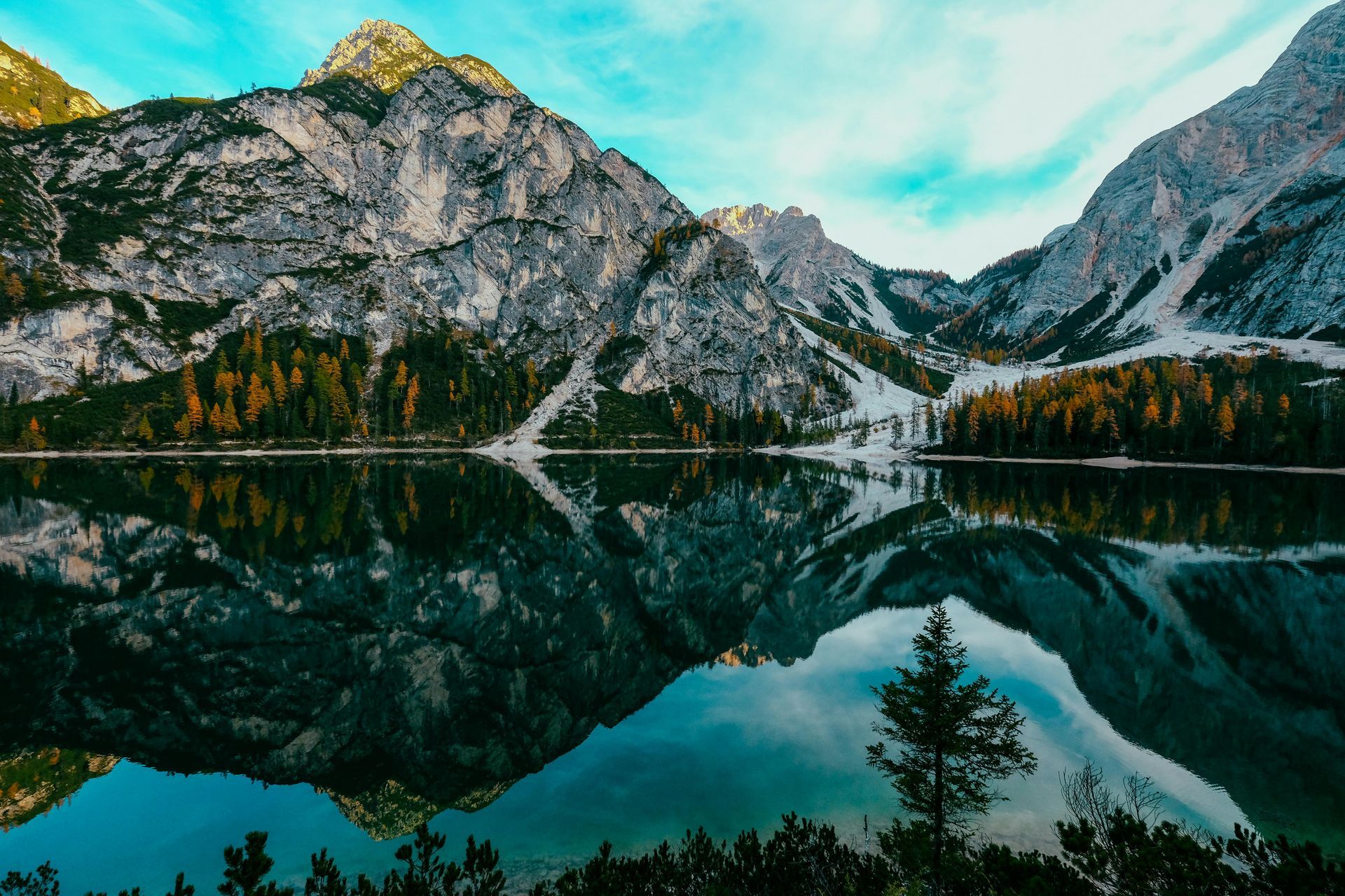 Un lago con montañas al fondo y árboles en primer plano.