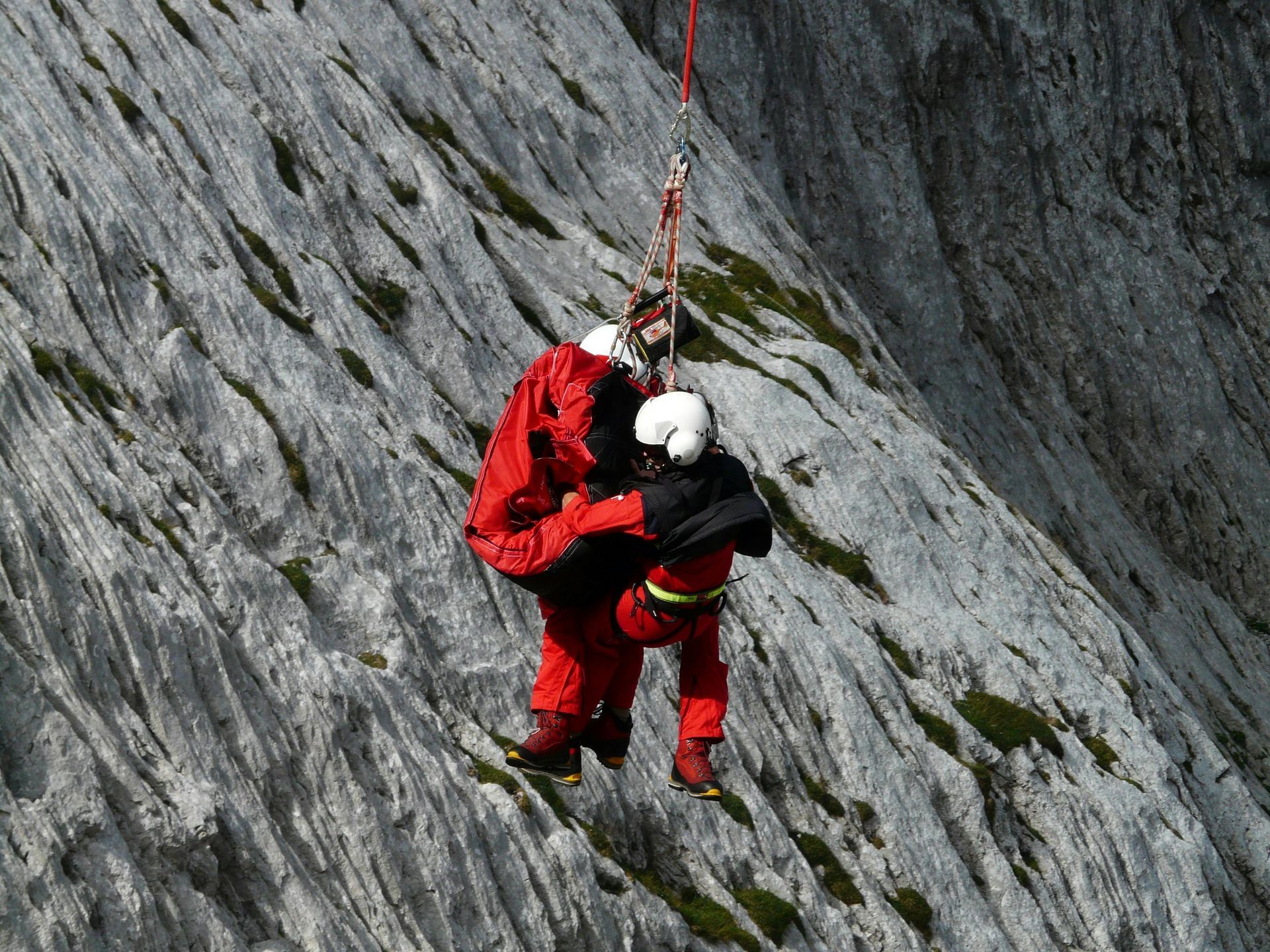 Un hombre con una chaqueta roja lleva a otro hombre a una montaña.