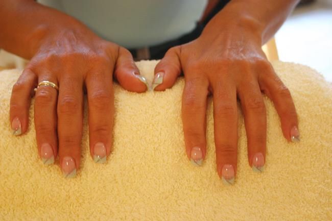 Eine Frau bekommt eine Massage mit den Händen auf einem Handtuch