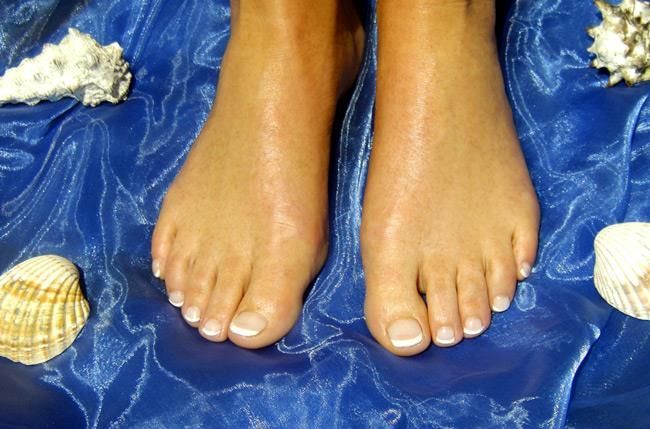 Die Füße einer Frau auf einem blauen Tuch mit Muscheln