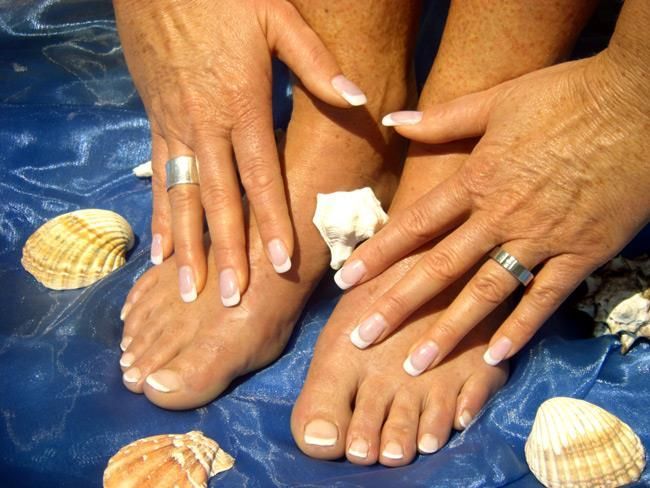 Füße und Hände einer Frau mit Muscheln im Hintergrund