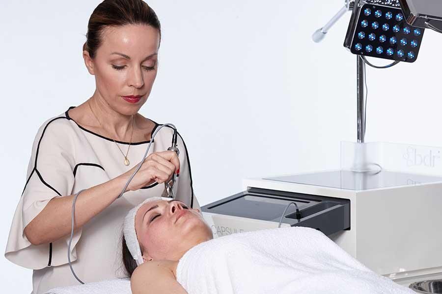 Eine Frau liegt auf einem Bett und bekommt eine Gesichtsbehandlung.