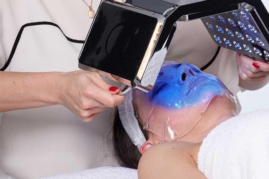 Eine Frau bekommt eine blaue Maske aufs Gesicht.