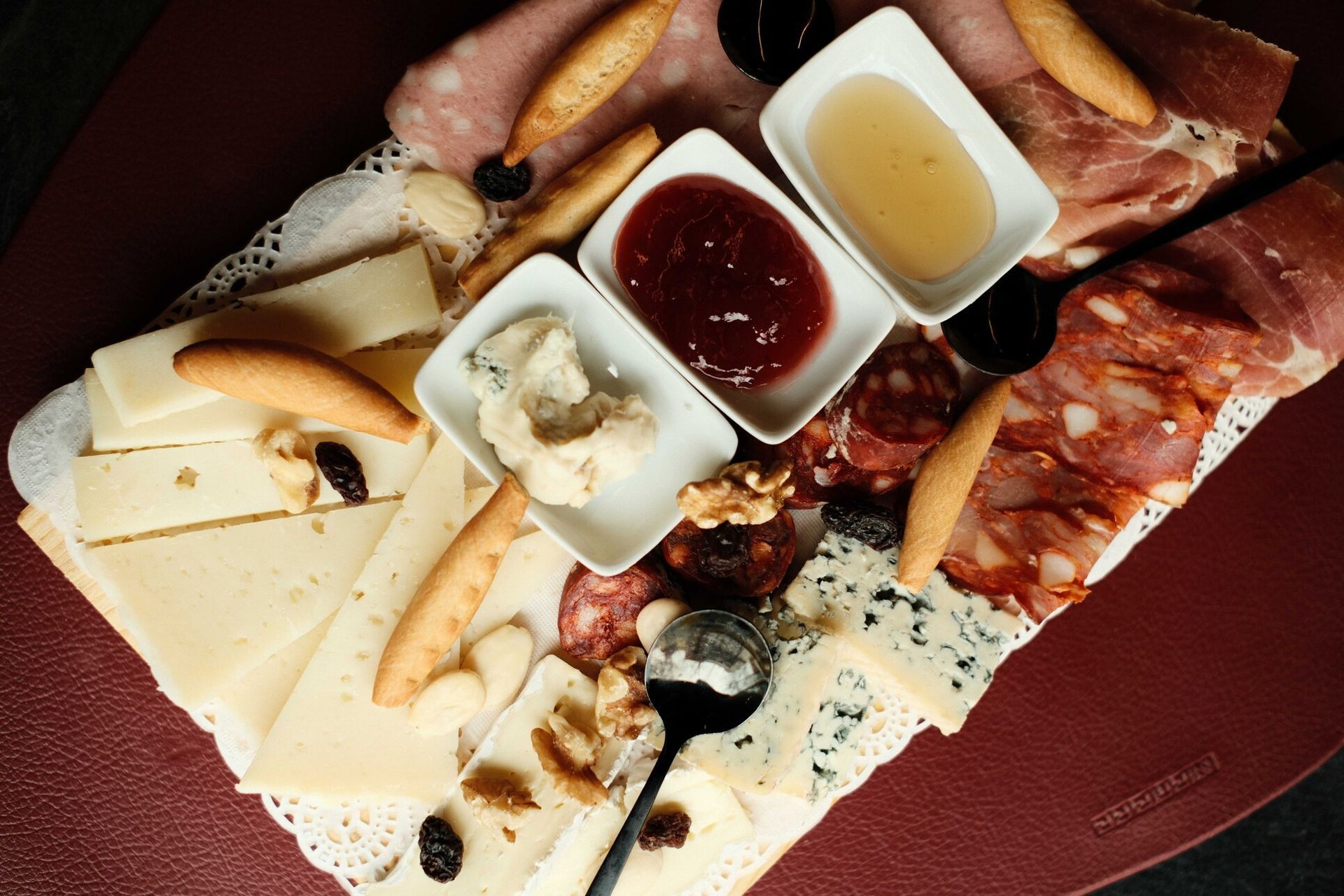 Tabla de embutidos con quesos, carnes, miel, mermelada y galletas.