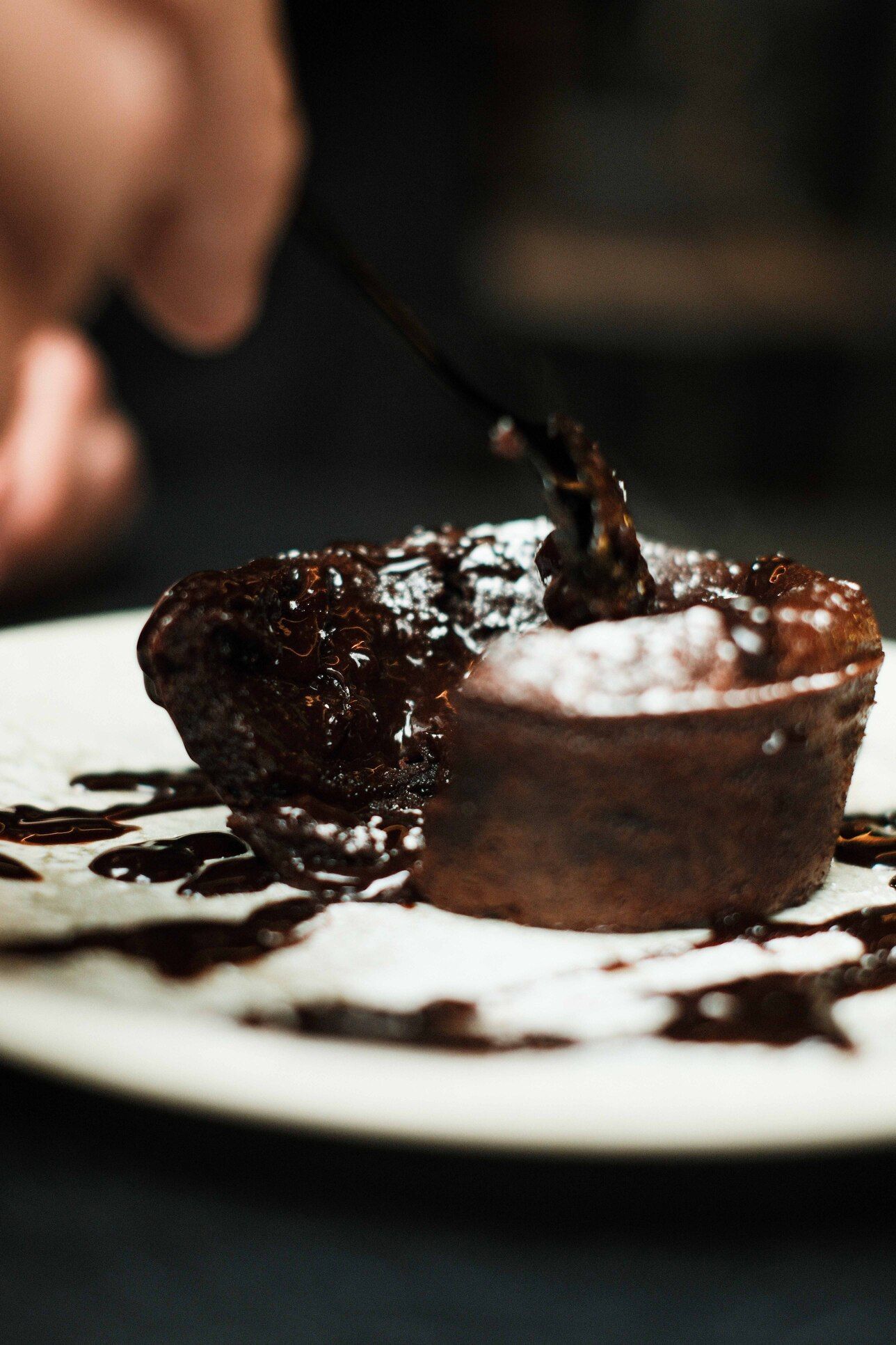 Pastel de chocolate derretido en un plato blanco, servido con un tenedor.