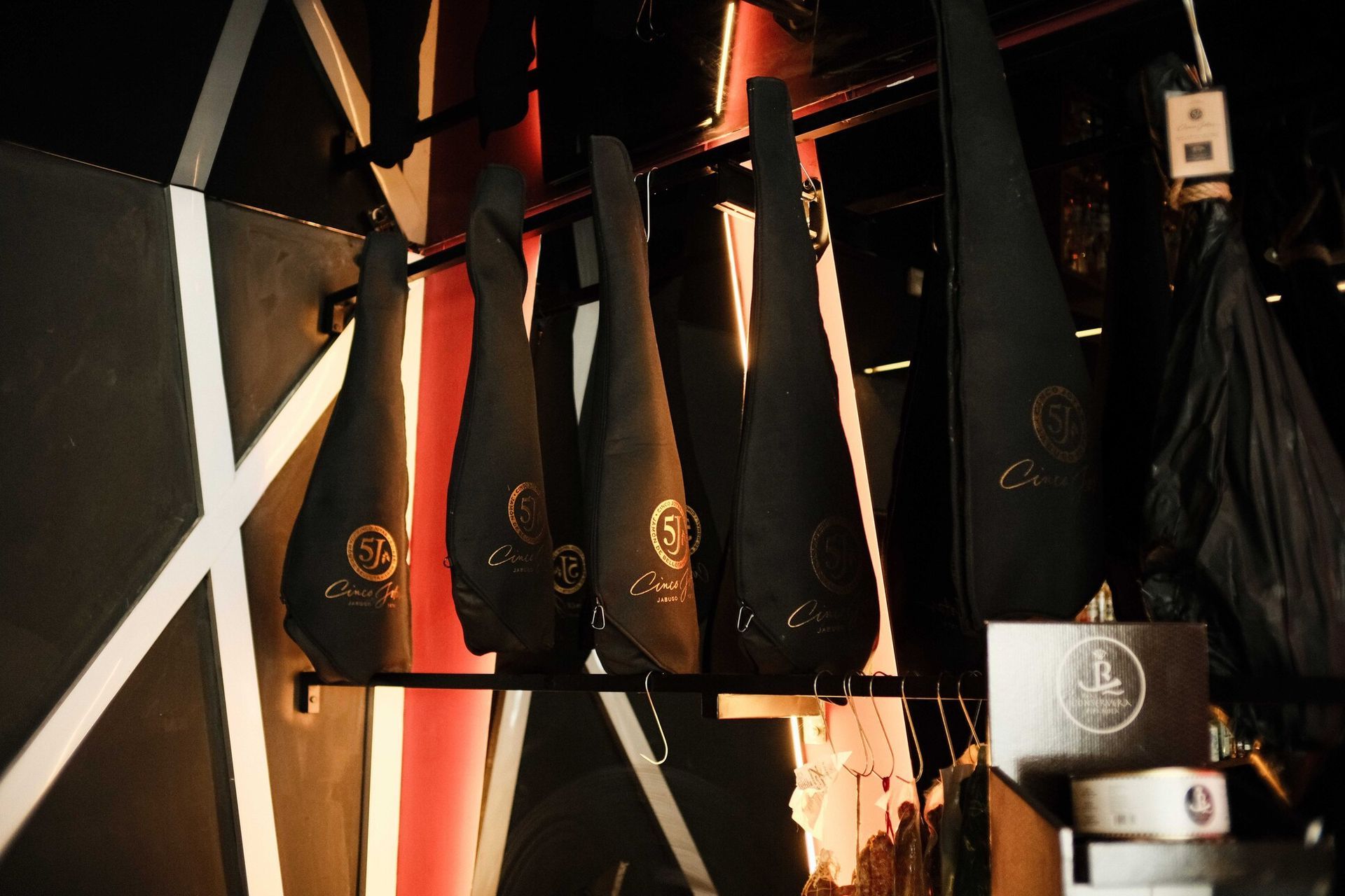 Botellas cubiertas de negro colgadas en un estante frente a una pared con dibujos geométricos.