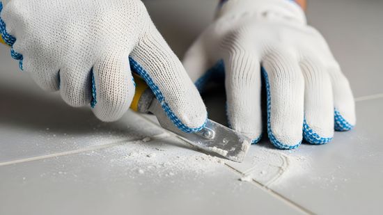 Nahaufnahme einer Baustelle, die Drahtgitter über Dämmplatten zeigt, die teilweise mit frischem grauen Mörtel in der Nähe eines Fensterrahmens bedeckt sind.