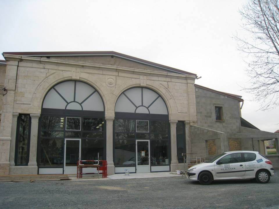 Bâtiment avec de grandes fenêtres cintrées et une voiture garée.