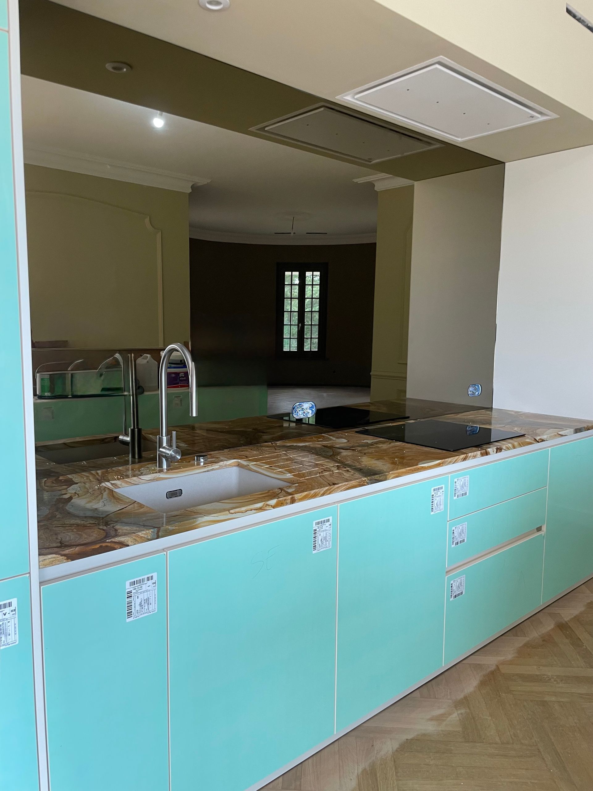 Un îlot de cuisine moderne avec des armoires bleu clair et un comptoir en pierre, comprenant un évier et un robinet dans une pièce.