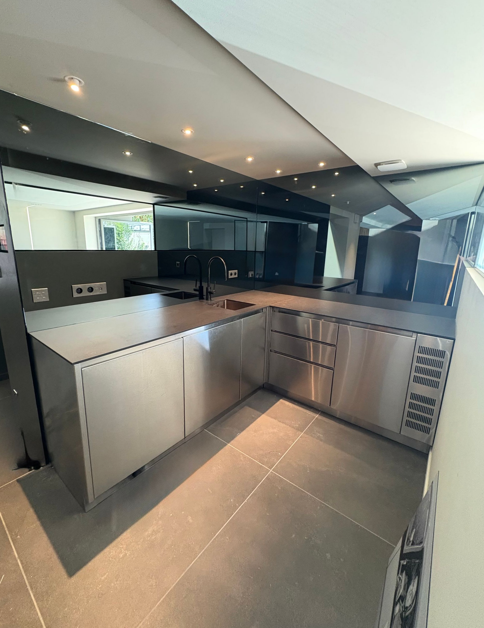Intérieur d'une chambre avec une fenêtre et une porte de douche sombres. Tête de lit marron et applique murale visibles.