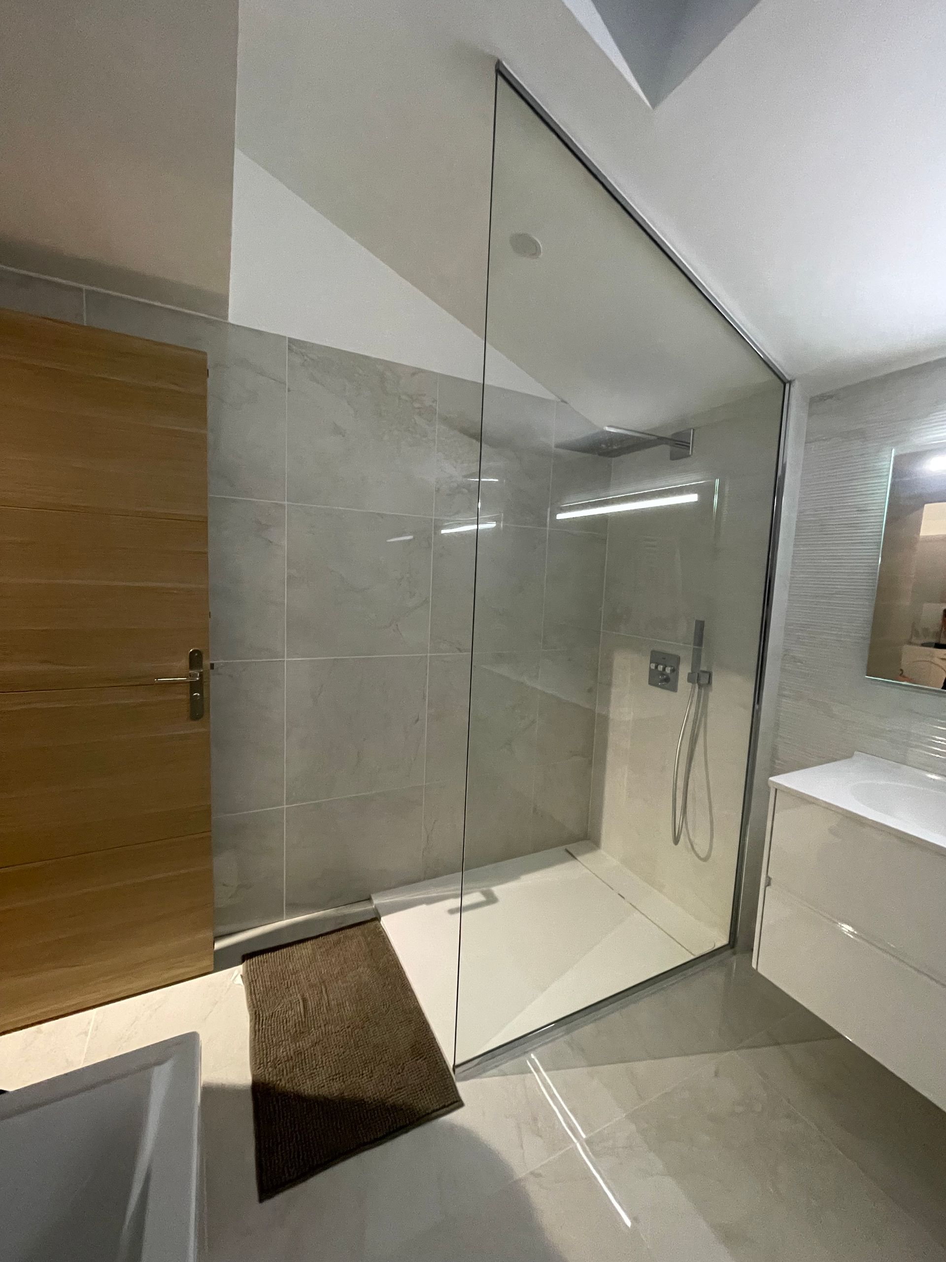 Salle de bains moderne et spacieuse avec parquet, deux baignoires, grand miroir et murs d'accent vert foncé.