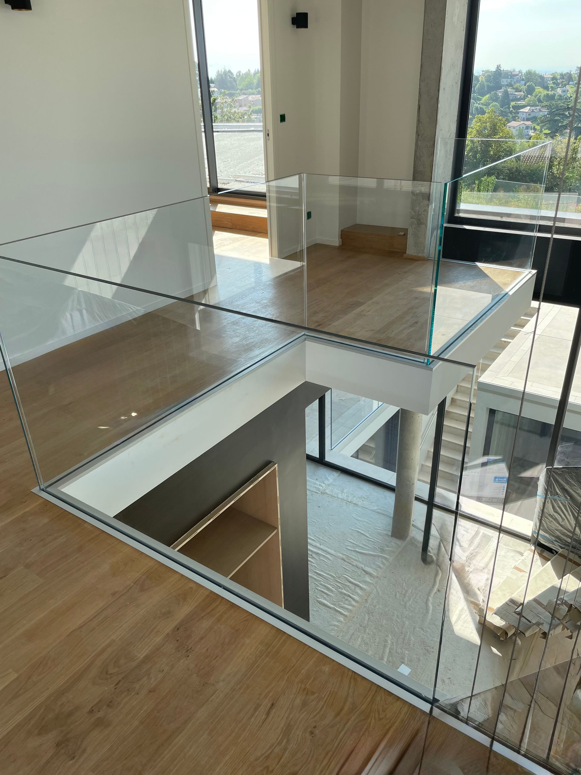 Intérieur moderne avec balustrade en verre, parquet et vue.