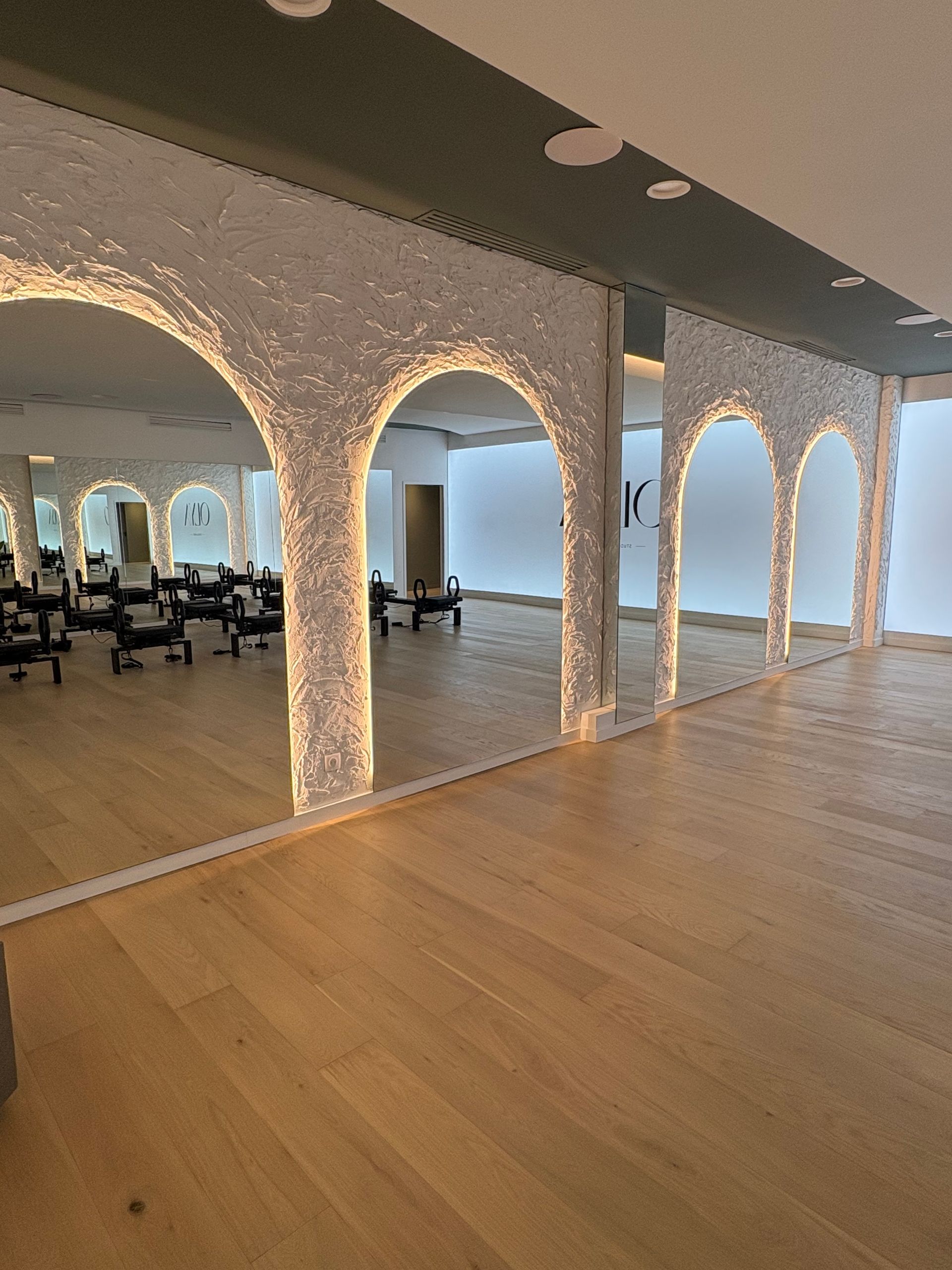 Un espace intérieur caractérisé par un mur de miroirs allant du sol au plafond reflétant des colonnes blanches.