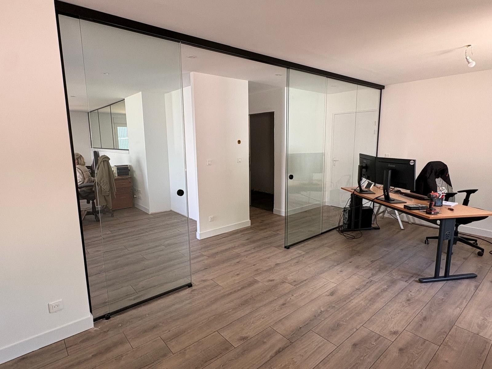 Pièce moderne vide avec portes coulissantes en verre, parquet et bureau debout avec équipement informatique