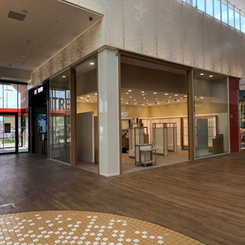 Local commercial vide dans un centre commercial, avec vitrines et parquet.