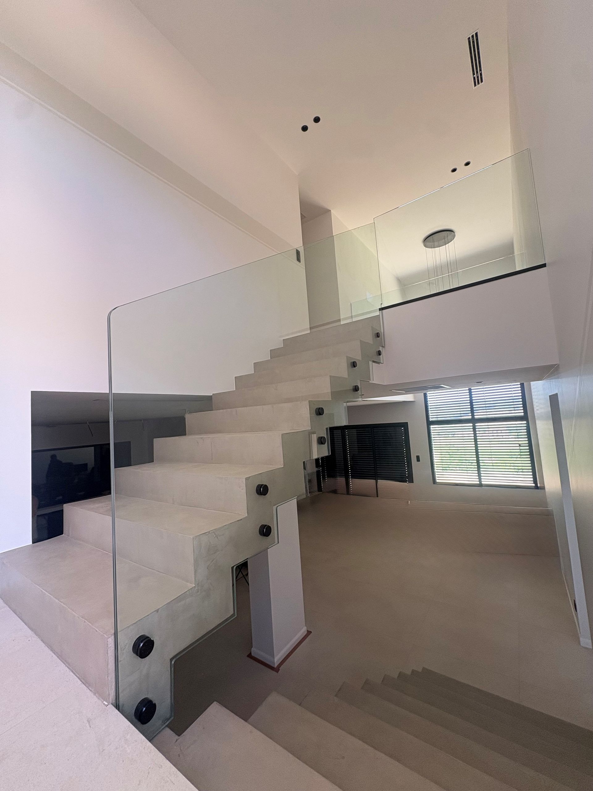 Intérieur moderne avec un escalier à balustrade en verre menant à une mezzanine