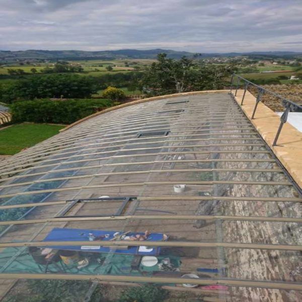 Construction sur un toit en verre incurvé avec une vue panoramique sur l'extérieur en arrière-plan. Outils et matériaux sur place.