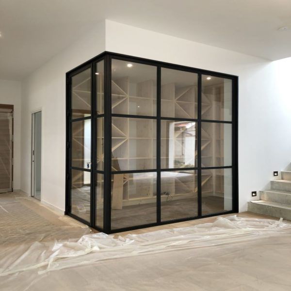 Une cloison moderne avec des cadres en métal noir et de grandes baies vitrées, intégrant une structure de casier à vin en bois.