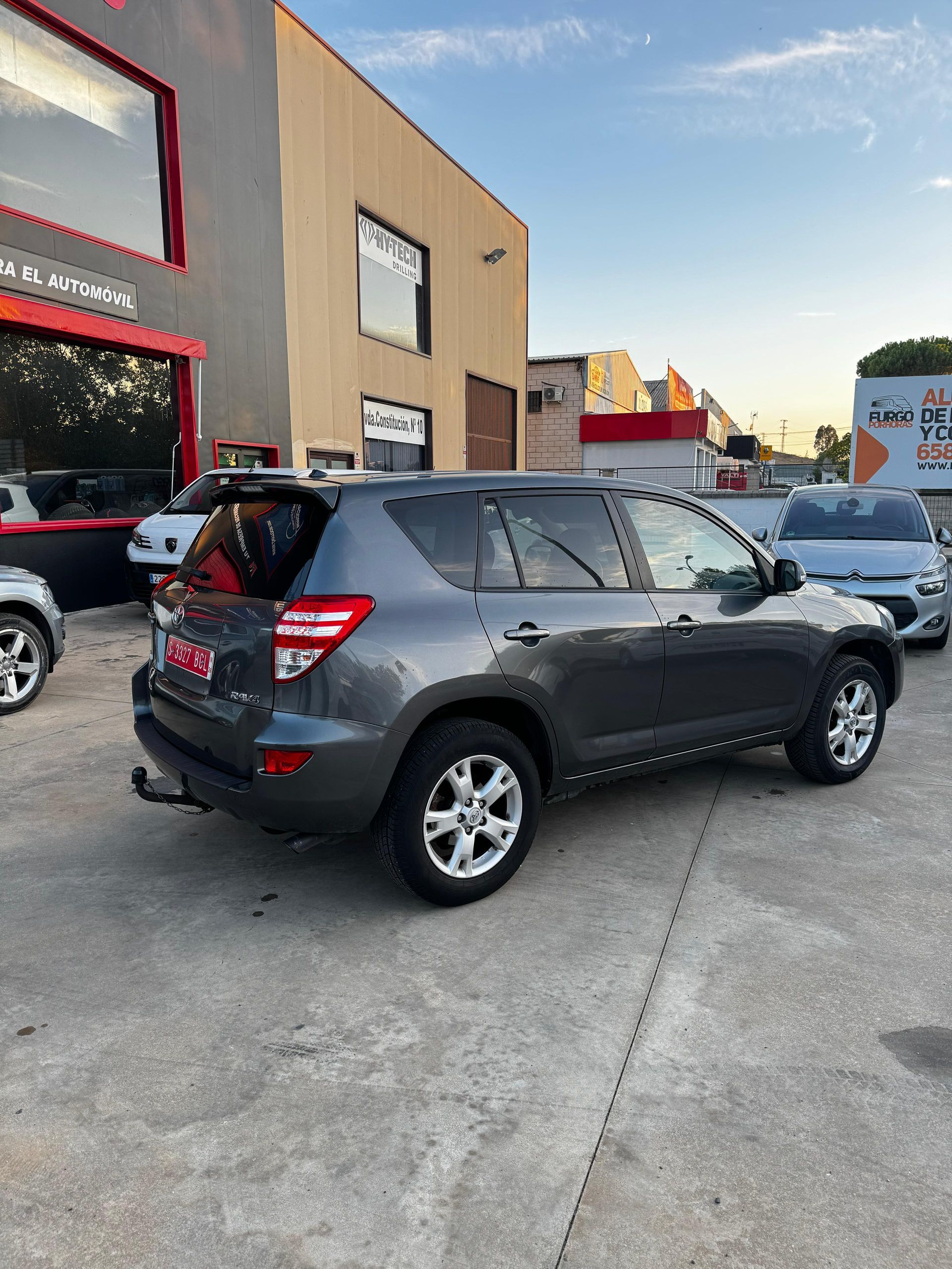 Toyota RAV4 gris estacionado frente a un edificio.