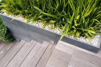 Treppenbereich aus Holz und Grünpflanzen mit kleinen Steinen