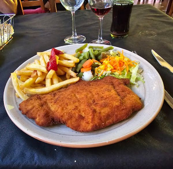 Un plato de comida con patatas fritas y verduras en una mesa.