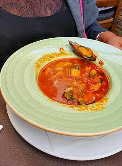 Una mujer sostiene un tazón de sopa con mejillones.
