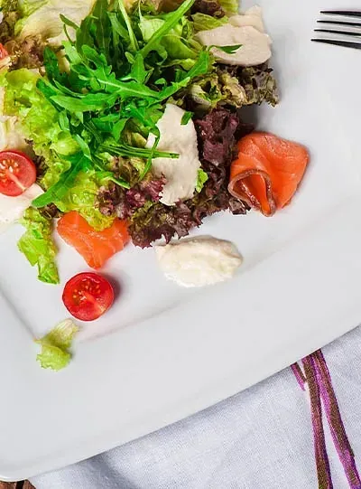 Un plato blanco cubierto con una ensalada y un tenedor.