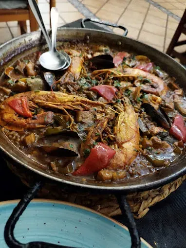 Una cacerola con comida y una cuchara dentro sobre una mesa.