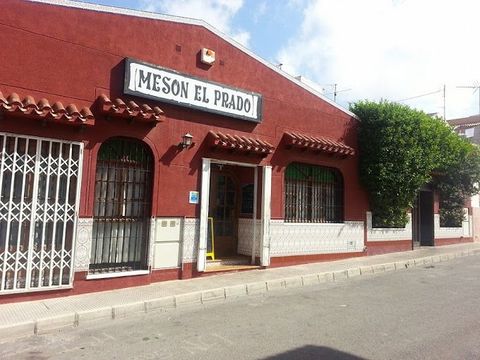Un edificio rojo con un cartel que dice Meson El Prado