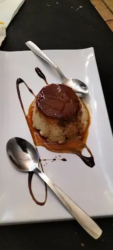 Un plato blanco cubierto con un postre y dos cucharas.