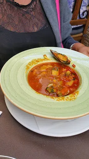 Una mujer está sentada en una mesa sosteniendo un tazón de sopa.