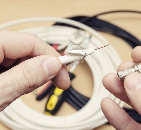 Una persona sostiene un destornillador y un cable en sus manos.