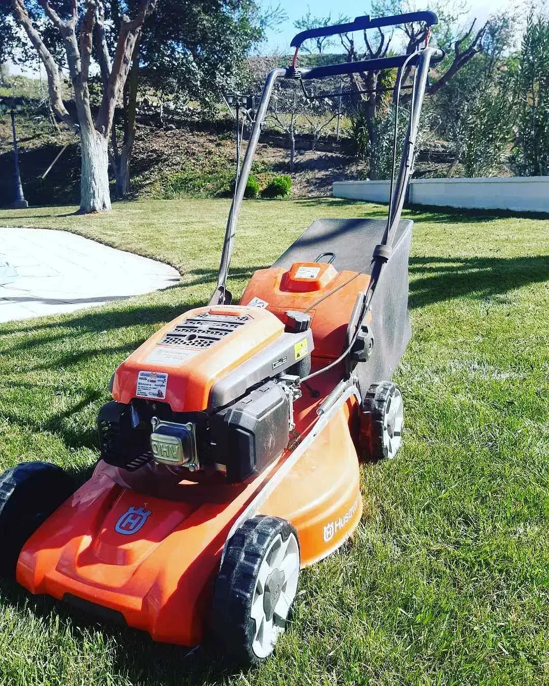 Una cortadora de césped Husqvarna naranja está estacionada en el césped.