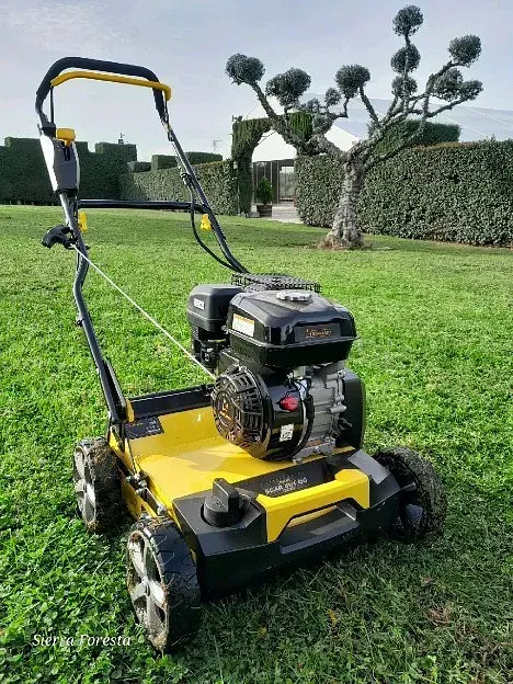 Una cortadora de césped de color amarillo y negro se encuentra sobre un césped verde y exuberante.