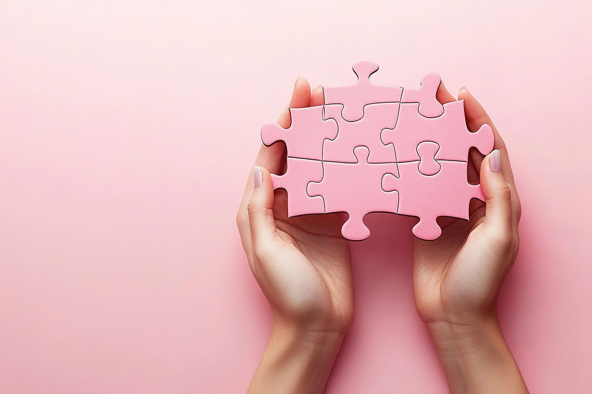 Eine Person hält ein rosa Puzzleteil in den Händen.