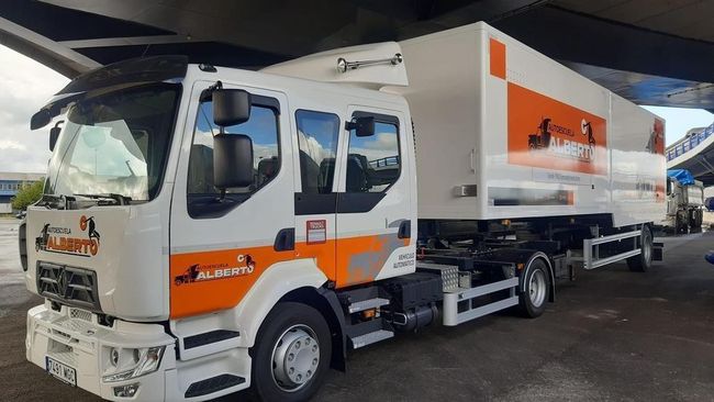 Un camión blanco y naranja está estacionado debajo de un puente.