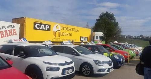 Una fila de coches están aparcados delante de un camión amarillo.