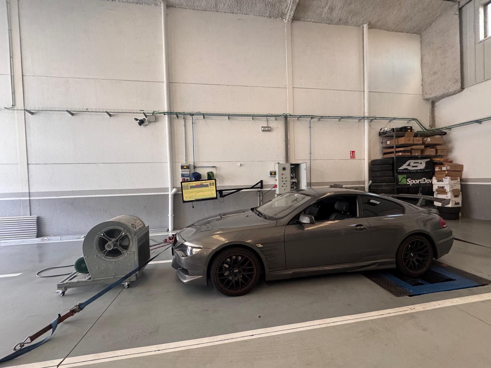 Un Volkswagen Golf azul oscuro aparcado frente a un moderno edificio gris en un día soleado. Otro coche aparcado a lo lejos.