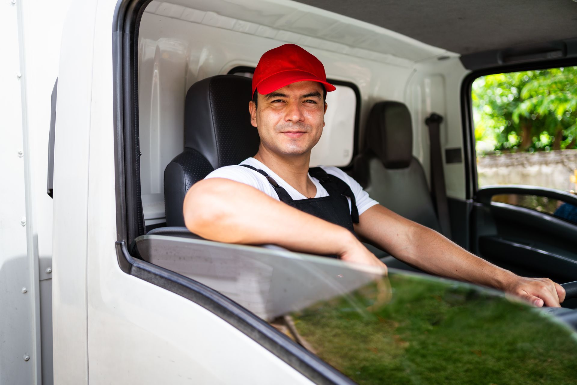Chauffeur au volant d'un camion portant une casquette rouge et fixant l'objectif