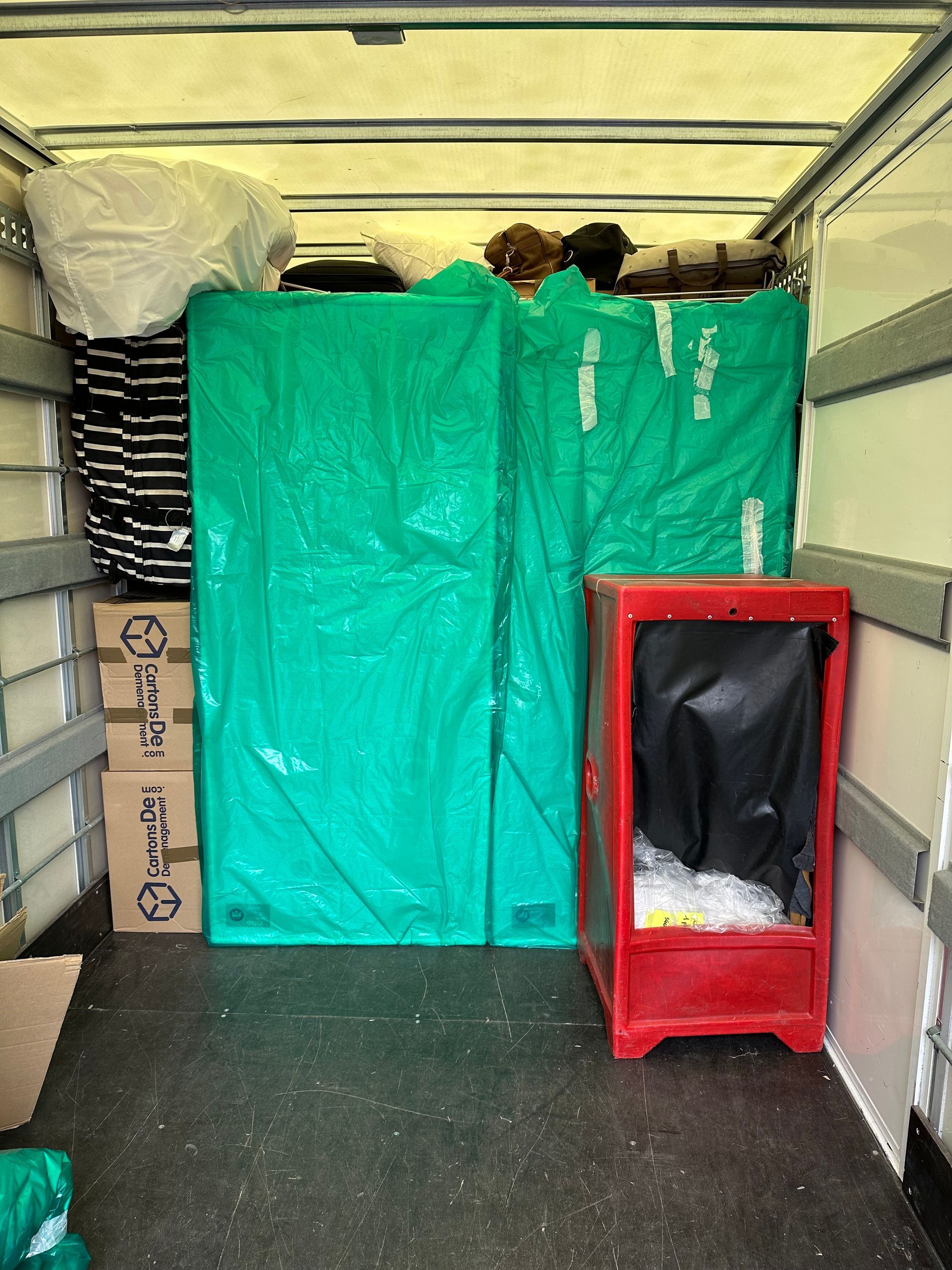 Intérieur de camion avec carton et mobilier emballé par une bâche verte