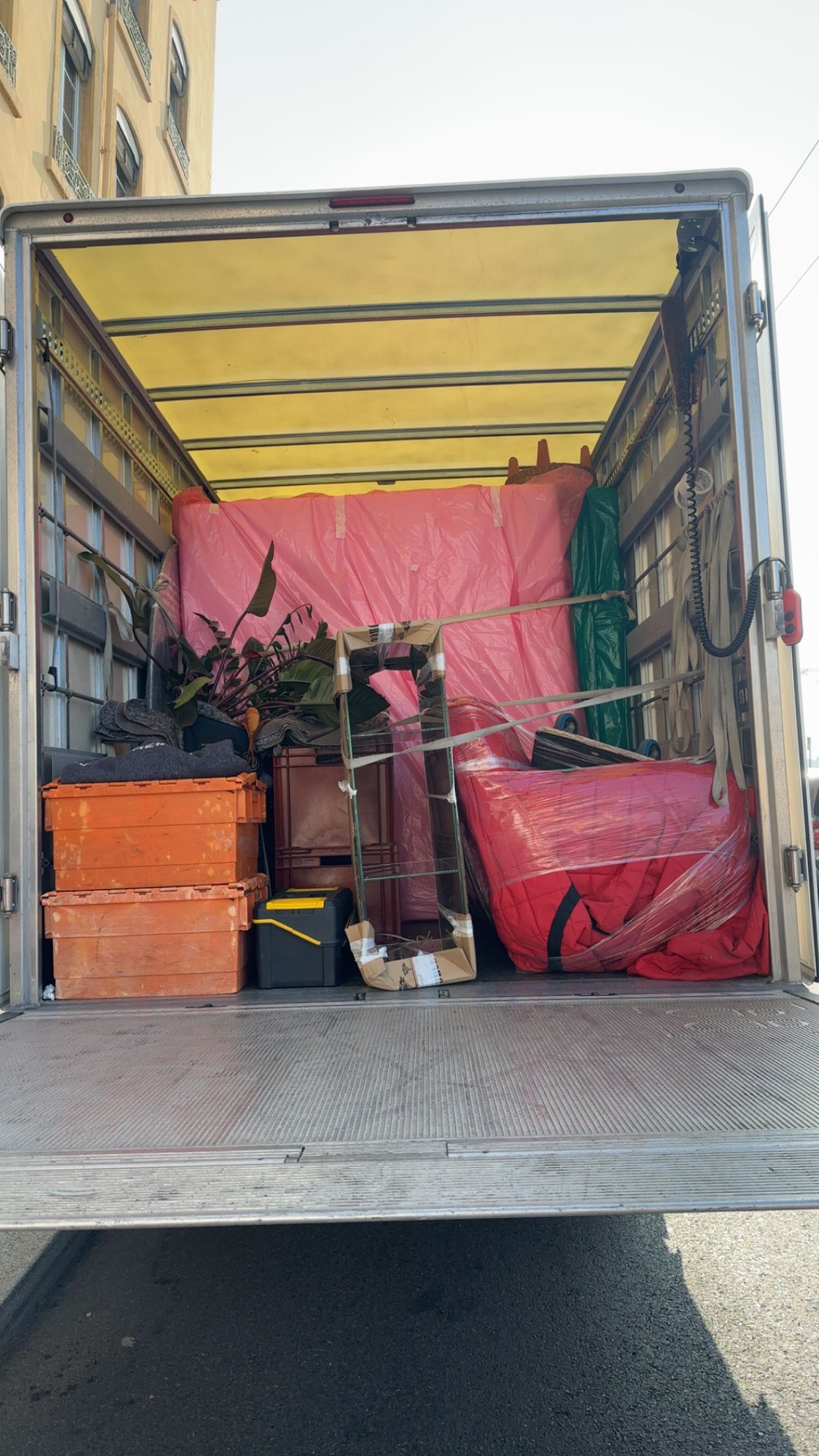Intérieur de camion de déménagement rempli avec plantes et meubles sous couvertures