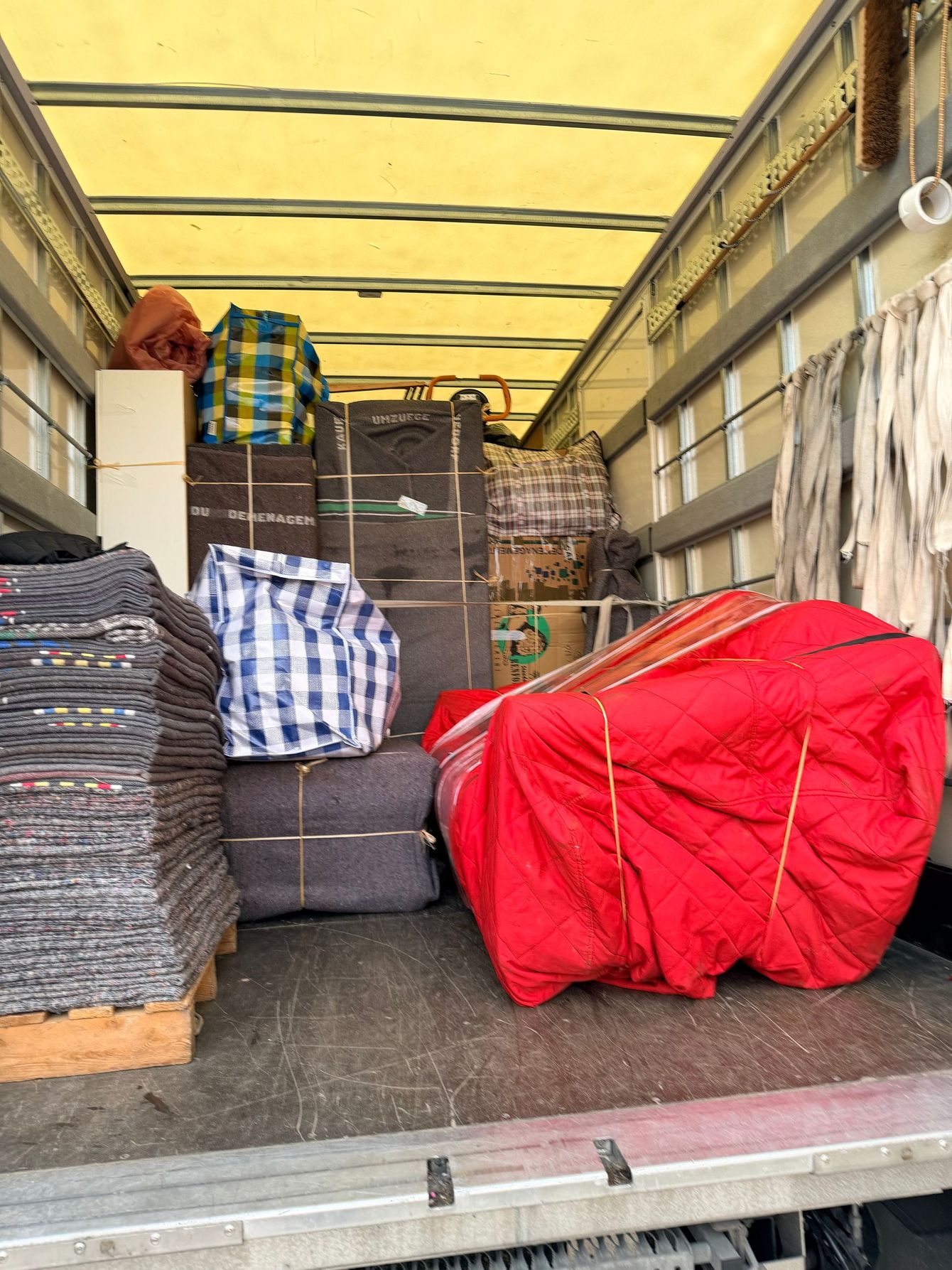 Camion de marchandises chargé de sacs empilés et d'articles emballés sous un plafond recouvert d'une bâche jaune