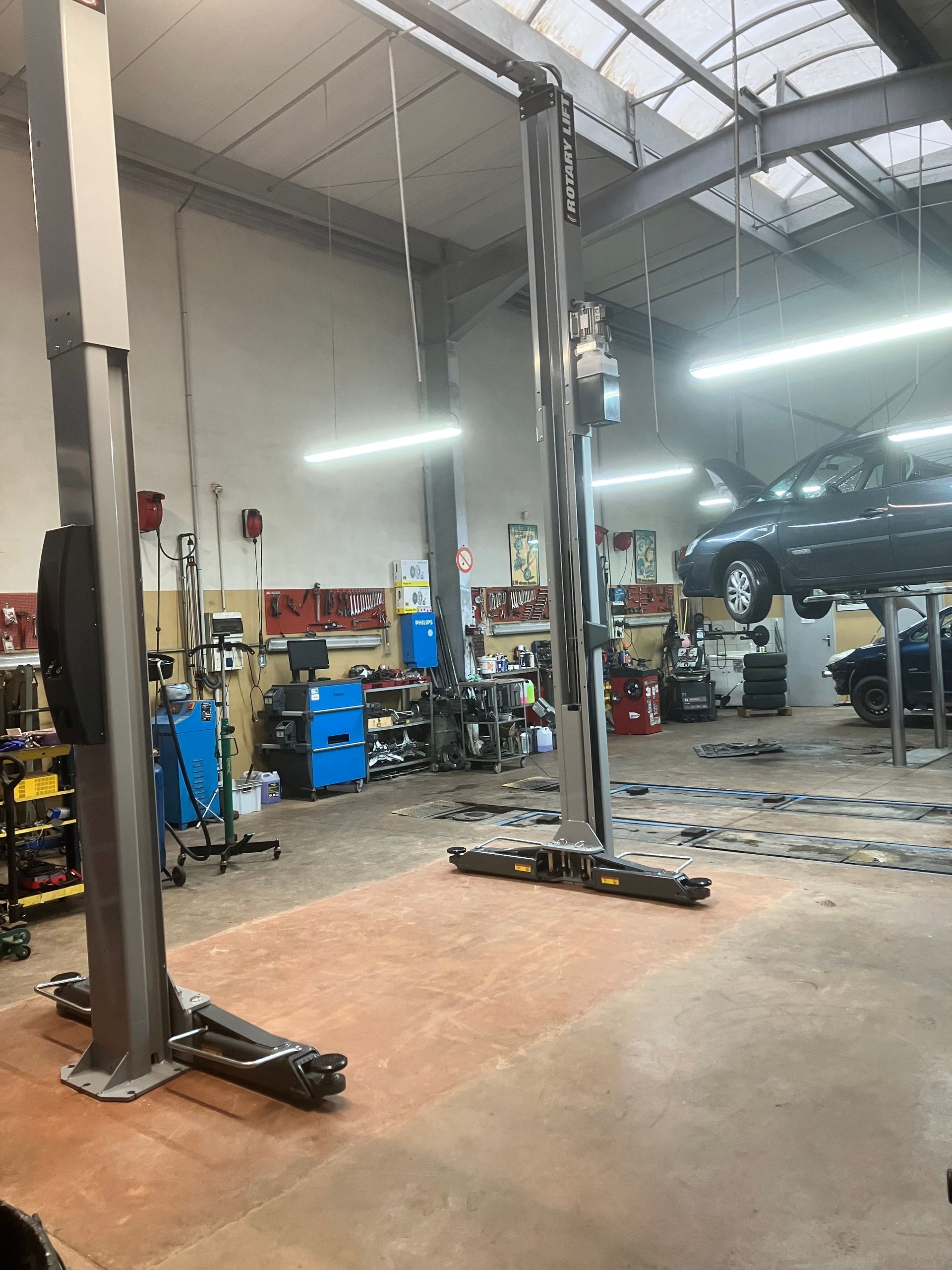 Pont élévateur à deux colonnes dans un garage avec un véhicule dessus.