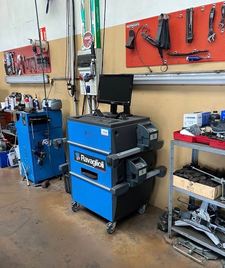 Une machine bleue pour la géométrie des roues Ravaglioli dans un garage, avec un écran d'ordinateur.
