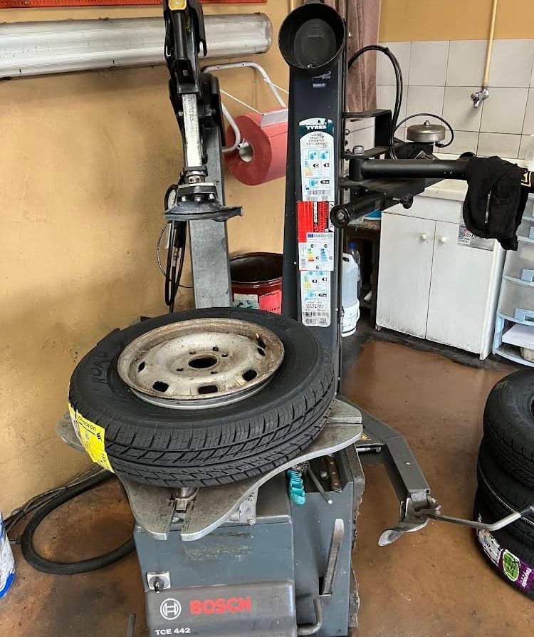 Pneu et roue montés sur une machine à pneus dans un garage.